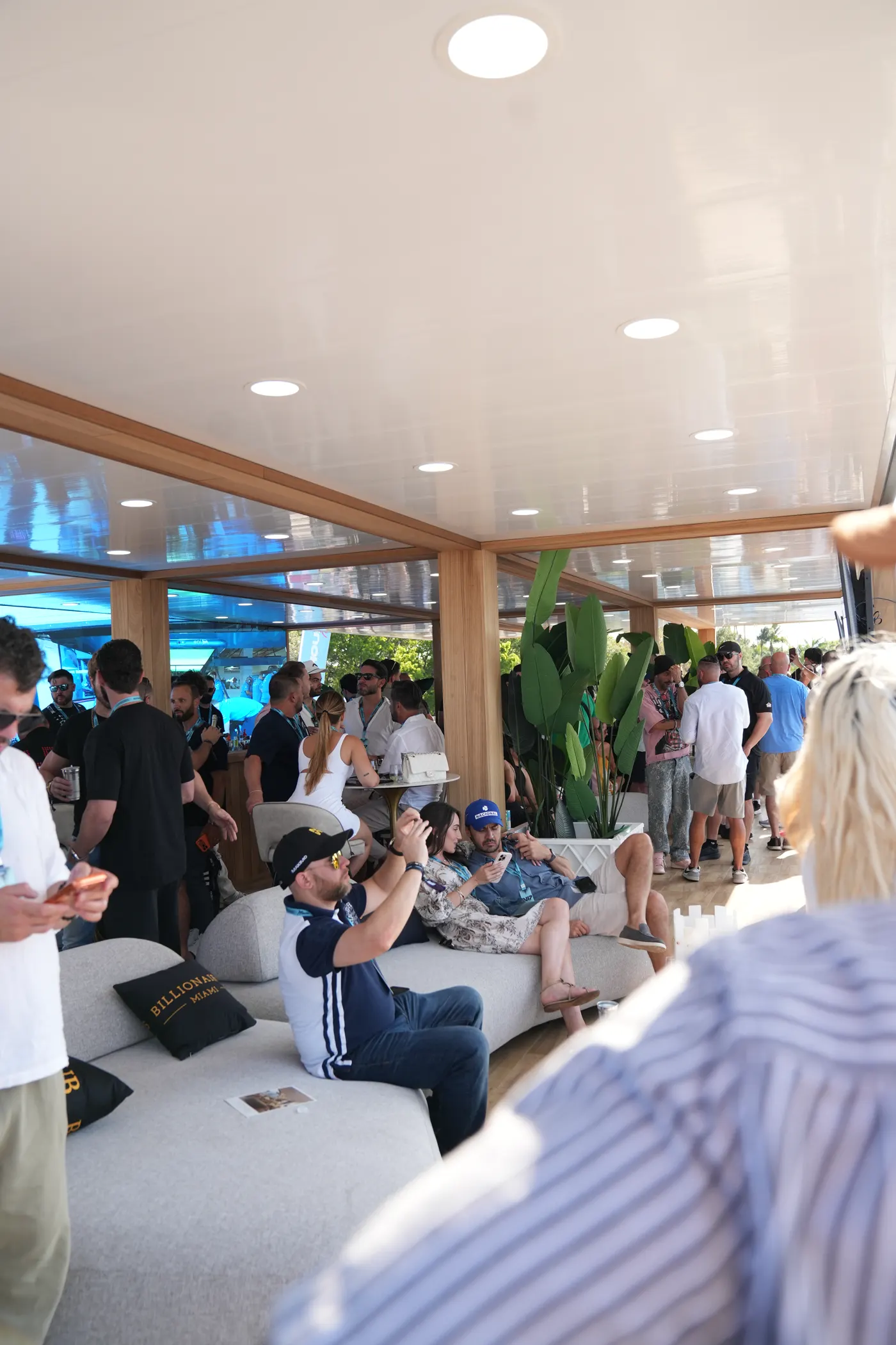 Interior de la suite GRID House, invitados sentados y de pie, el circuito tras el cristal